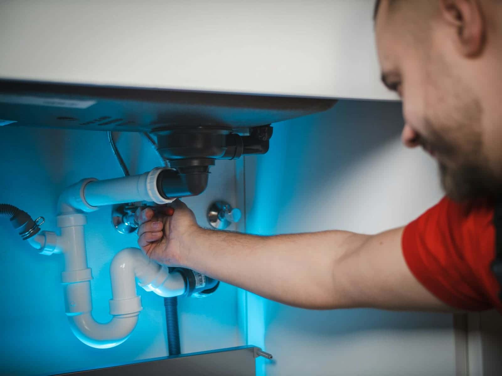 Plumber fitting a drain trap under a sink